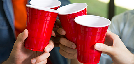 Four red plastic cups being in a cheers formation